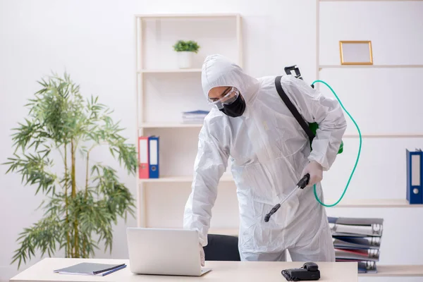 Young male contractor disinfecting office in industrial espionag — Stock Photo, Image