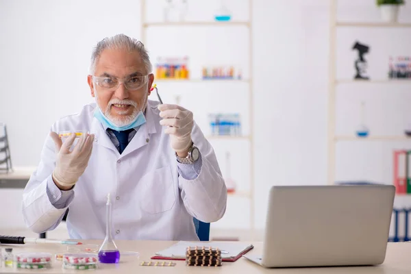 Old male chemist in drug synthesis concept — Stock Photo, Image
