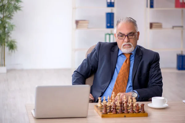 Old businessman playing chess at workplace — Stock Photo, Image