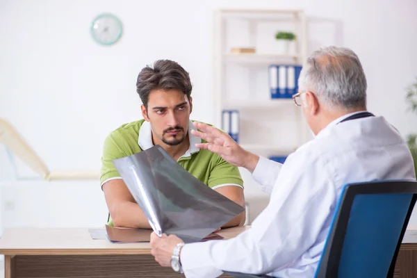 Jovem paciente masculino visitando velho médico radiologista masculino — Fotografia de Stock