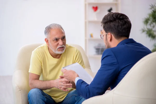 Oude man op bezoek bij jonge mannelijke psychotherapeut — Stockfoto