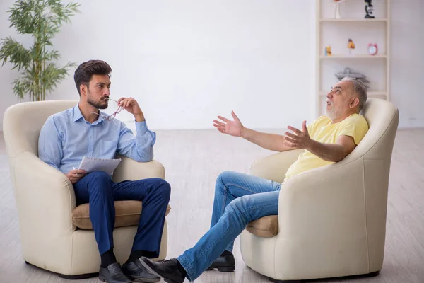 Velho visitando jovem psicoterapeuta masculino — Fotografia de Stock