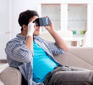 Eli yaralı bir adam sanal gerçeklik gözlüğü takıyor.