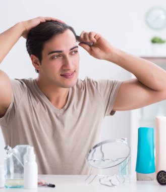 Genç yakışıklı adam aynaya bakıyor.