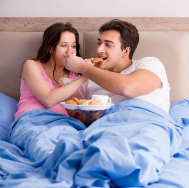 Mutlu bir aile yatakta kahvaltı yapıyor.