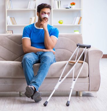 Koltuk değnekli yaralı bir adam evde iyileşiyor.