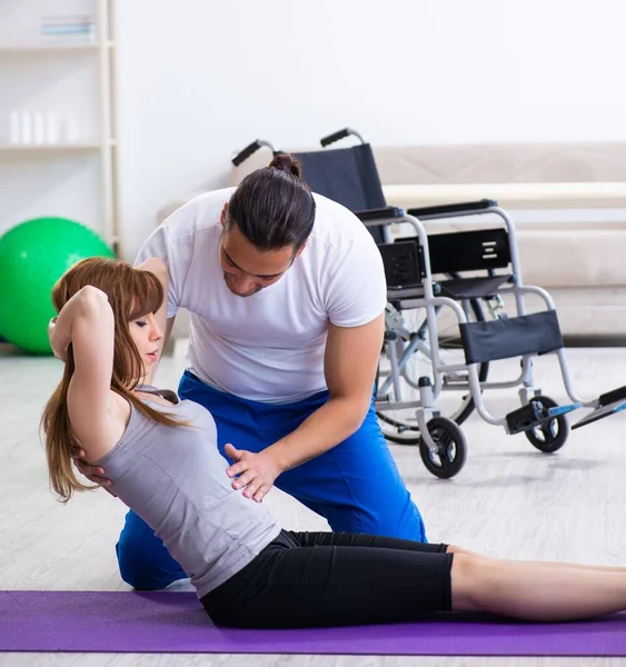 Male physiotherapist doing exercises with injured woman on floor — Stock Photo, Image