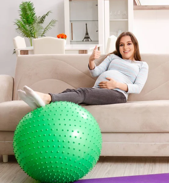 Genç hamile kadın evde spor egzersizleri yapıyor.