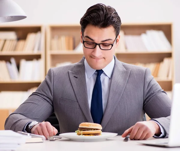 Hambriento empresario divertido comer sándwich de comida chatarra — Foto de Stock