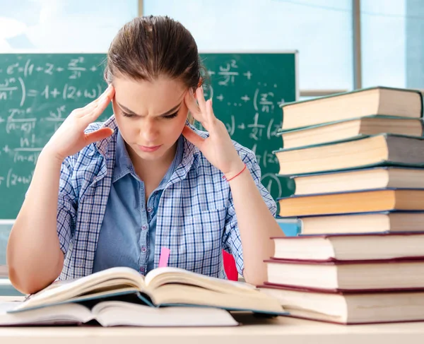 L'étudiante avec de nombreux livres assis dans la salle de classe — Photo