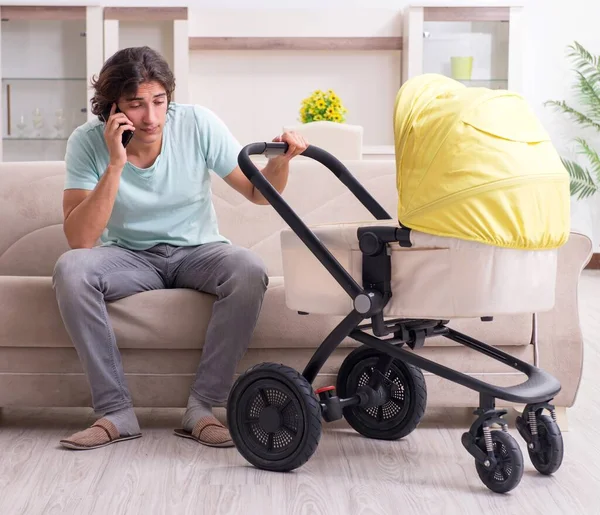 Ung man tar hand om barnet i barnvagn — Stockfoto