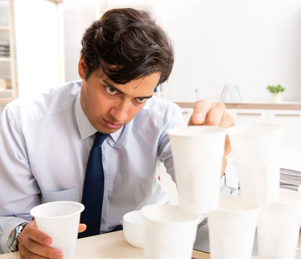The young employee building pyramid from plastic cups — Stock Photo, Image