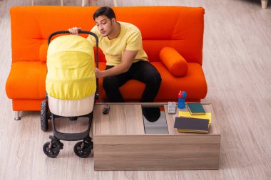 Genç adam evde yeni doğan çocuğa bakıyor.