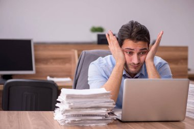 Ofisteki aşırı işten memnun olmayan genç bir erkek işçi.