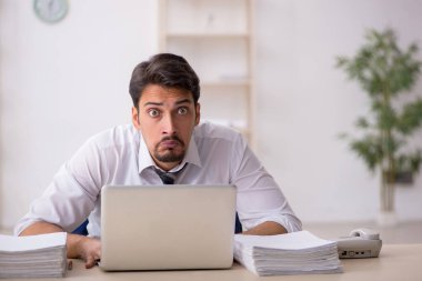 Ofisteki aşırı işten memnun olmayan genç bir erkek işçi.