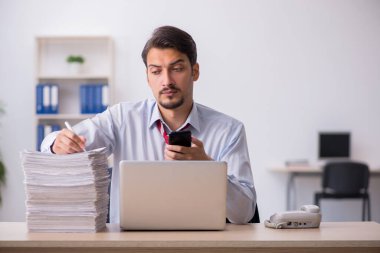 Genç erkek çalışan işyerinde oturuyor.