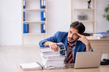 Genç bir erkek çalışan ve ofiste çok fazla iş var.