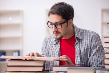 Genç bir erkek öğrenci ve sınıfta çok fazla kitap var.