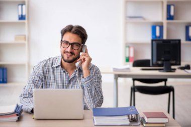 Genç erkek çalışan ofiste oturuyor.