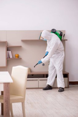 Young male contractor disinfecting at home