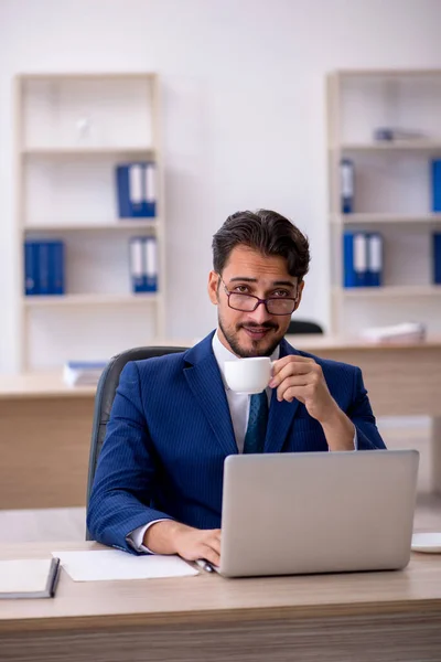 Ung manlig anställd dricker kaffe under rasten — Stockfoto