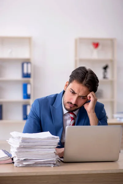 Ung manlig anställd och för mycket arbete på kontoret — Stockfoto