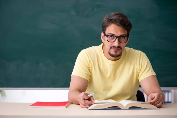 Young male student in front of blackboard — Stock Photo, Image