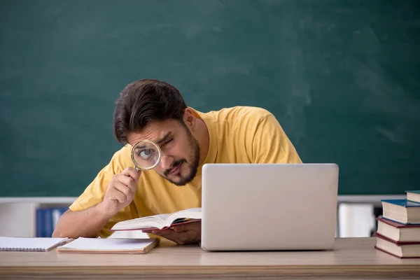 Ung manlig student förbereder sig för tentor i klassrummet — Stockfoto