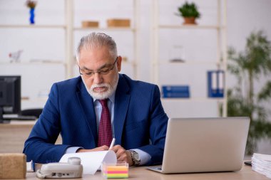 Ofiste çalışan yaşlı bir erkek.