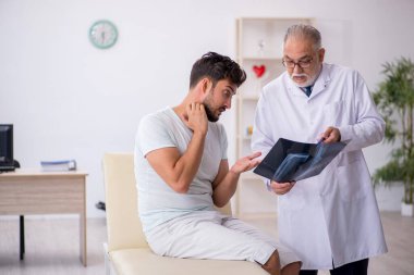 Genç erkek hasta yaşlı erkek doktor radyolojisti ziyaret ediyor.