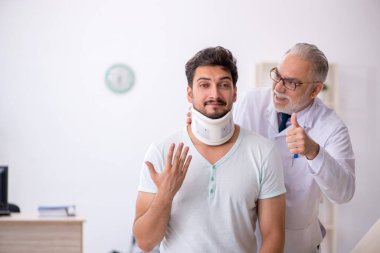 Genç boynu yaralı erkek hasta yaşlı erkek doktoru ziyaret ediyor.
