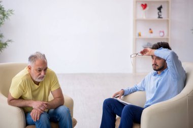 Yaşlı adam genç erkek psikoterapisti ziyaret ediyor.