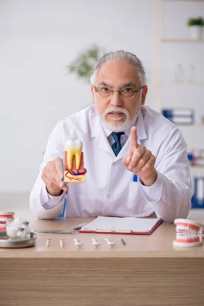 Oude mannelijke tandarts werkzaam in de kliniek — Stockfoto