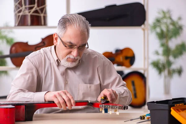 Alte männliche Reparaturkraft repariert Musikinstrumente am Arbeitsplatz — Stockfoto