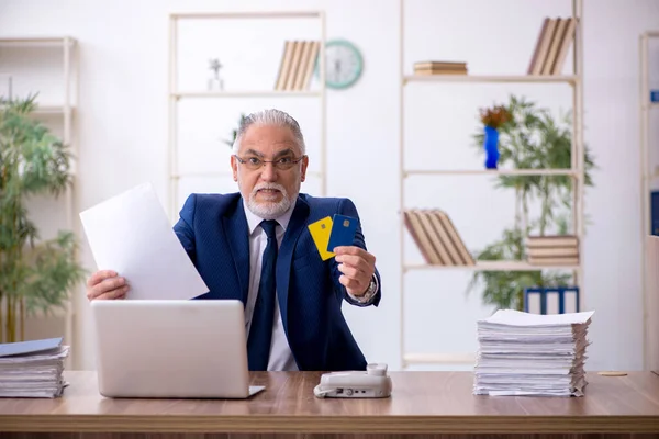 Старий працівник тримає кредитну картку в офісі — стокове фото