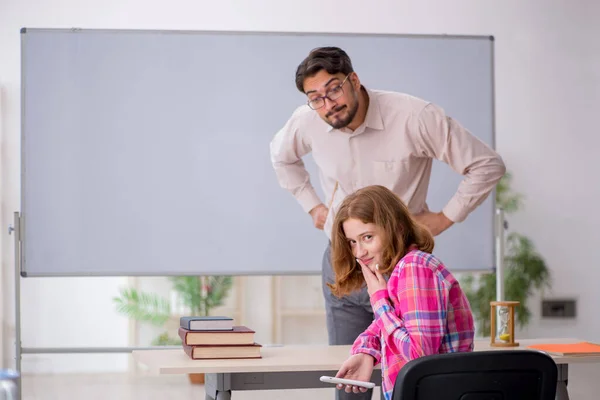 Fiatal férfi tanár és vörös hajú lány az osztályteremben — Stock Fotó