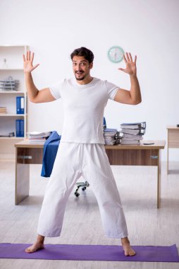 Genç erkek çalışan ofiste spor egzersizleri yapıyor.