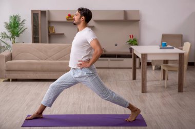 Genç adam evde spor yapıyor.