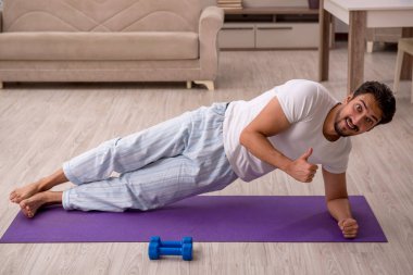 Genç adam evde spor yapıyor.