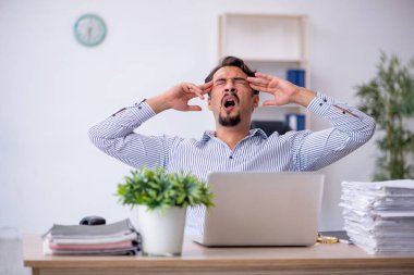 Ofisteki aşırı işten memnun olmayan genç bir erkek işçi.