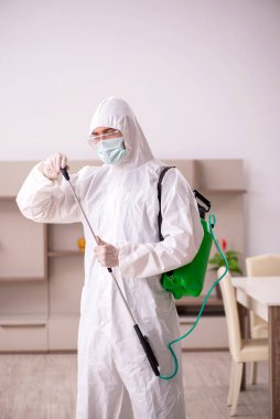 Genç erkek müteahhit evde haşere kontrolü yapıyor.