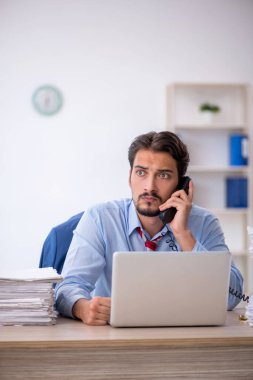 Genç bir erkek çalışan ve ofiste çok fazla iş var.