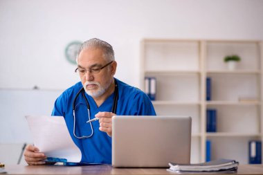 Klinikte çalışan yaşlı erkek doktor.