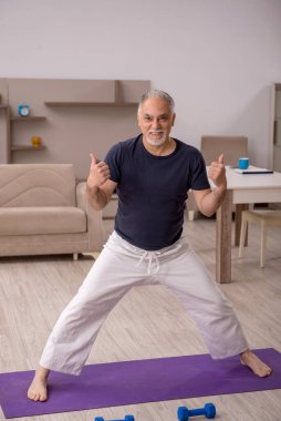 Yaşlı adam evde spor yapıyor.