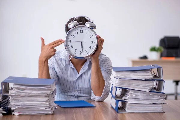 Young male employee and too much work in the office — Stock Photo, Image