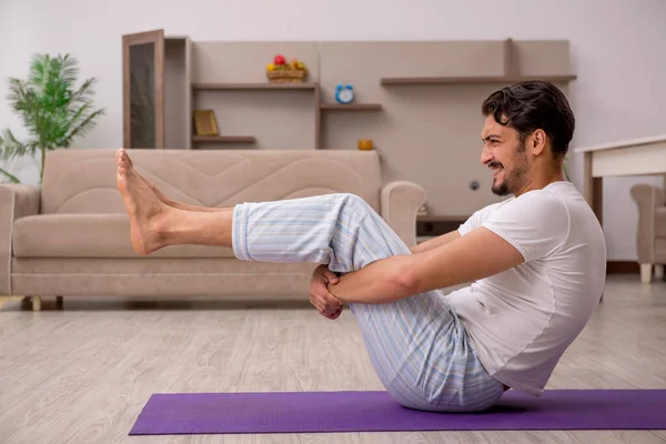 Giovane uomo che fa esercizi sportivi a casa — Foto Stock