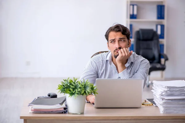 Ung mandlig medarbejder utilfreds med overdrevent arbejde på kontoret - Stock-foto