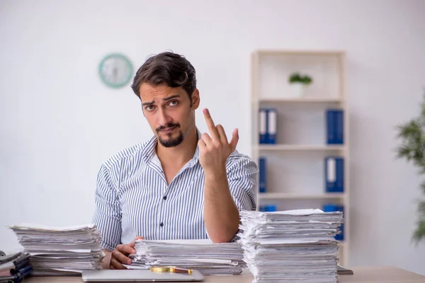 Молодой работник мужчина недоволен чрезмерной работой в офисе — стоковое фото