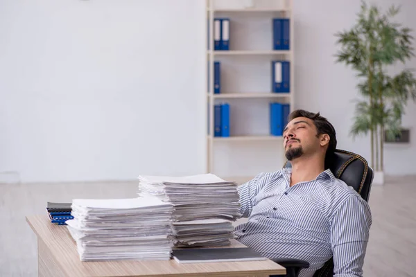 Jonge mannelijke werknemer ongelukkig met overmatig werk in het kantoor — Stockfoto