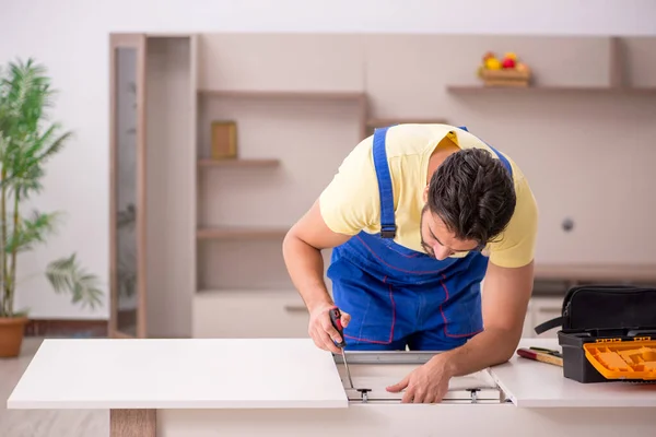 Młody mężczyzna stolarz naprawiający stół w domu — Zdjęcie stockowe